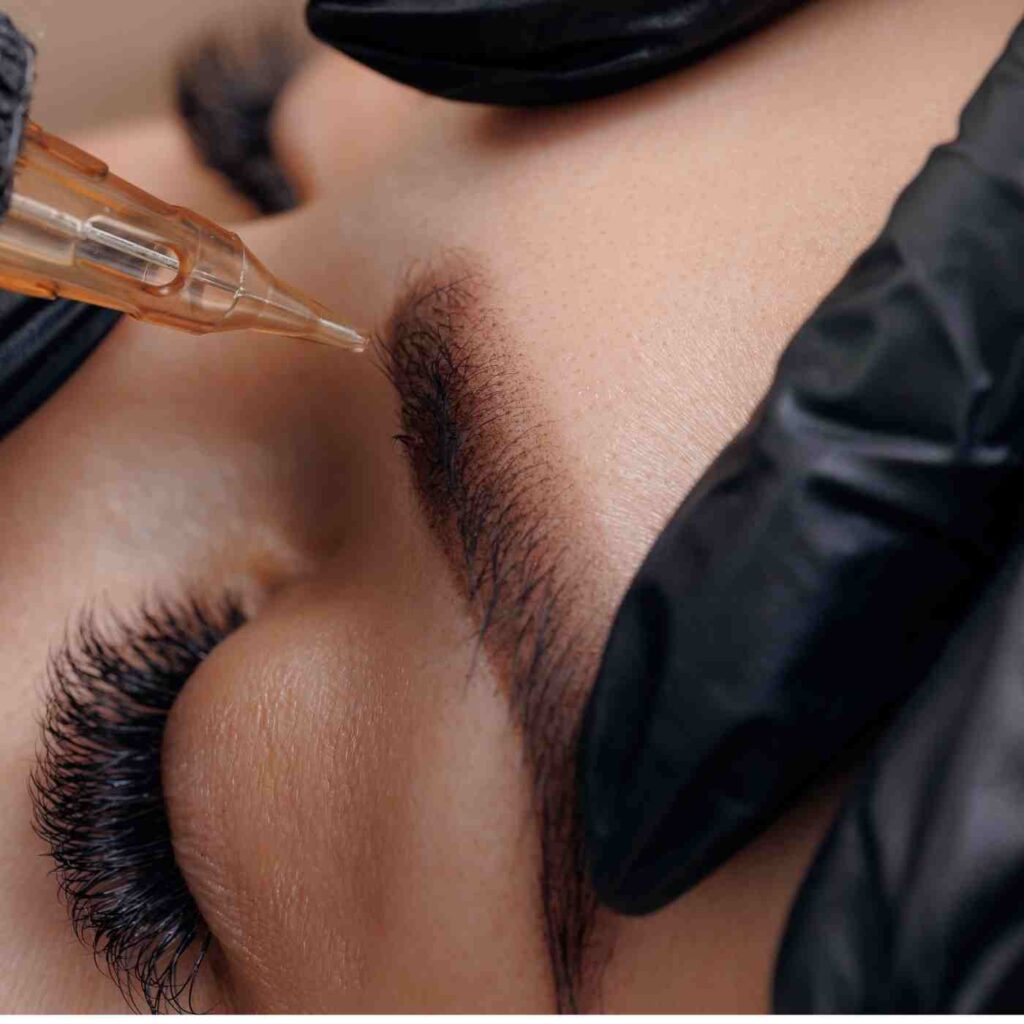 Cosmetic tattoo machine implanting pigment during professional brow tattoo procedure
